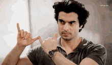 a man wearing a watch is making a funny face with his fingers