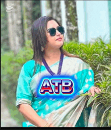 a woman wearing sunglasses and a blue shirt with atb written on it
