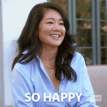 a woman in a blue shirt is smiling with the words so happy below her