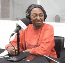 a woman wearing headphones is sitting in front of a microphone in a radio station .