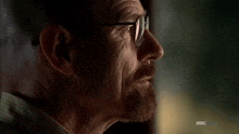 a close up of a man 's face with a beard and glasses with the letters a and mc visible