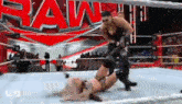 a woman is laying on the ground in a wrestling ring while a man is standing over her .