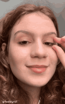 a woman with a nose ring is touching her eye