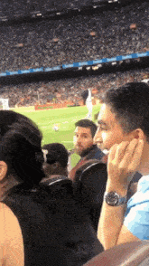 a man wearing a watch sits in a stadium watching a game