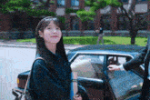 a woman is getting out of a car and holding a book