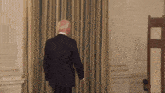a man in a suit walks through a doorway