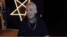 a man with a tattoo on his face is sitting in front of a microphone
