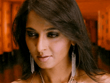 a close up of a woman 's face with a necklace and earrings
