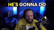 a man with a beard is sitting in front of a microphone with the words he 's gonna do behind him