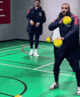 two men are playing basketball on a green court and one of them has the word nike on his jacket