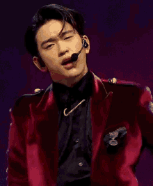 a man is wearing a red jacket and a microphone on his head .