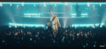 a man in a white robe is standing in front of a crowd with the word vevo on the bottom right