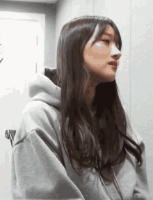 a woman wearing a grey hoodie looks to her left
