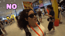 a woman wearing sunglasses stands in a crowded room with the word no above her head