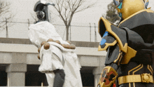 a man in a white robe is standing next to a man in a black and gold armor