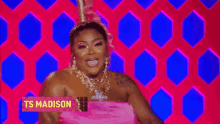 a woman in a pink dress is standing in front of a pink background .