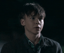 a young man in a plaid shirt and a black jacket