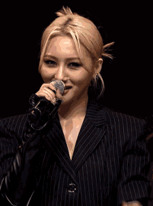 a woman in a suit is singing into a microphone .