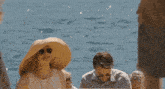 a woman wearing a straw hat is standing next to a man and a woman .
