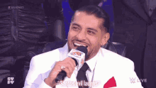 a man in a white suit and tie is laughing into a microphone with the words " santos evil laughs " below him