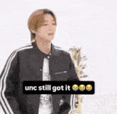 a young man wearing a black jacket and a white shirt with the words unc still got it