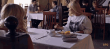 a woman sitting at a table with a plate of food and a ctc logo on the bottom right