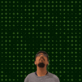 a man stands in front of a green background with the number 11 + 15 on it