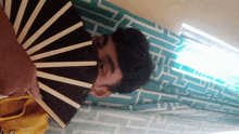 a person holding a fan in front of their face with a yellow shirt that says ' nc ' on it