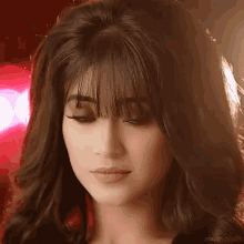 a close up of a woman 's face with long hair and bangs looking at the camera .