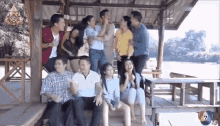 a group of people are posing for a picture while sitting on a wooden bench .