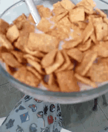 a glass bowl filled with crackers and milk with a spoon in it .