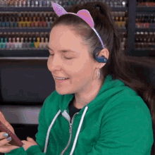 a woman wearing a headband with cat ears is smiling while holding a cell phone