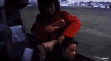 a woman in a red coat is sitting on a bus with a man .