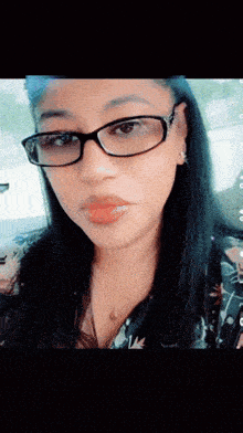 a close up of a woman wearing glasses and a floral shirt