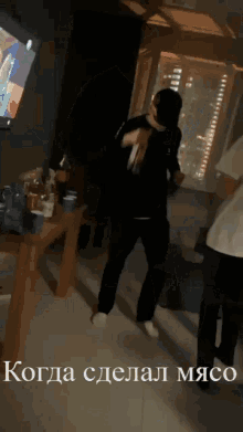 a man is dancing in front of a tv with the words когда сделал мясо on the bottom