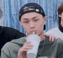 a man is drinking a drink through a straw from a cup .