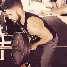 a man in a tank top is lifting a barbell