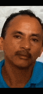 a man with a mustache wearing a blue shirt