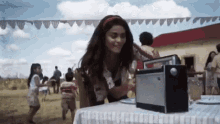 a woman is sitting at a table playing a radio