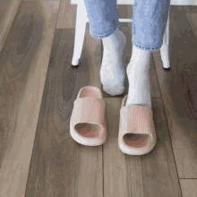 a person wearing white socks and pink sandals on a wood floor