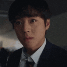 a close up of a man 's face in a suit and tie .