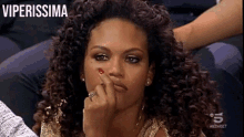 a woman with curly hair is sitting in front of a tv screen that says viperissima