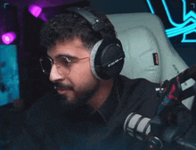 a man wearing headphones and glasses is sitting in a gaming chair