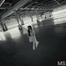 a woman in a white dress is standing in an empty warehouse with the letters ms on the bottom