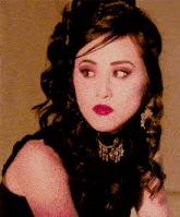 a close up of a woman 's face wearing a necklace and earrings