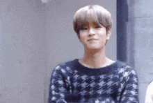 a young man wearing a blue and white sweater is looking at the camera