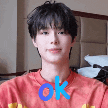 a young man wearing a red shirt with the word ok written on it