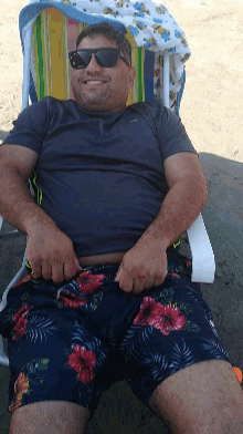 a man wearing sunglasses is laying on the beach