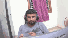 a man wearing headphones and a batman shirt looks at a computer screen