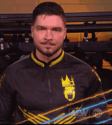 a man with his arms crossed is wearing a black and yellow jacket with a crown on it